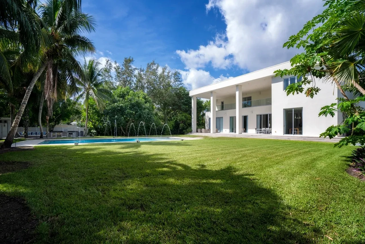 Modern white home exterior with pool and lush grounds